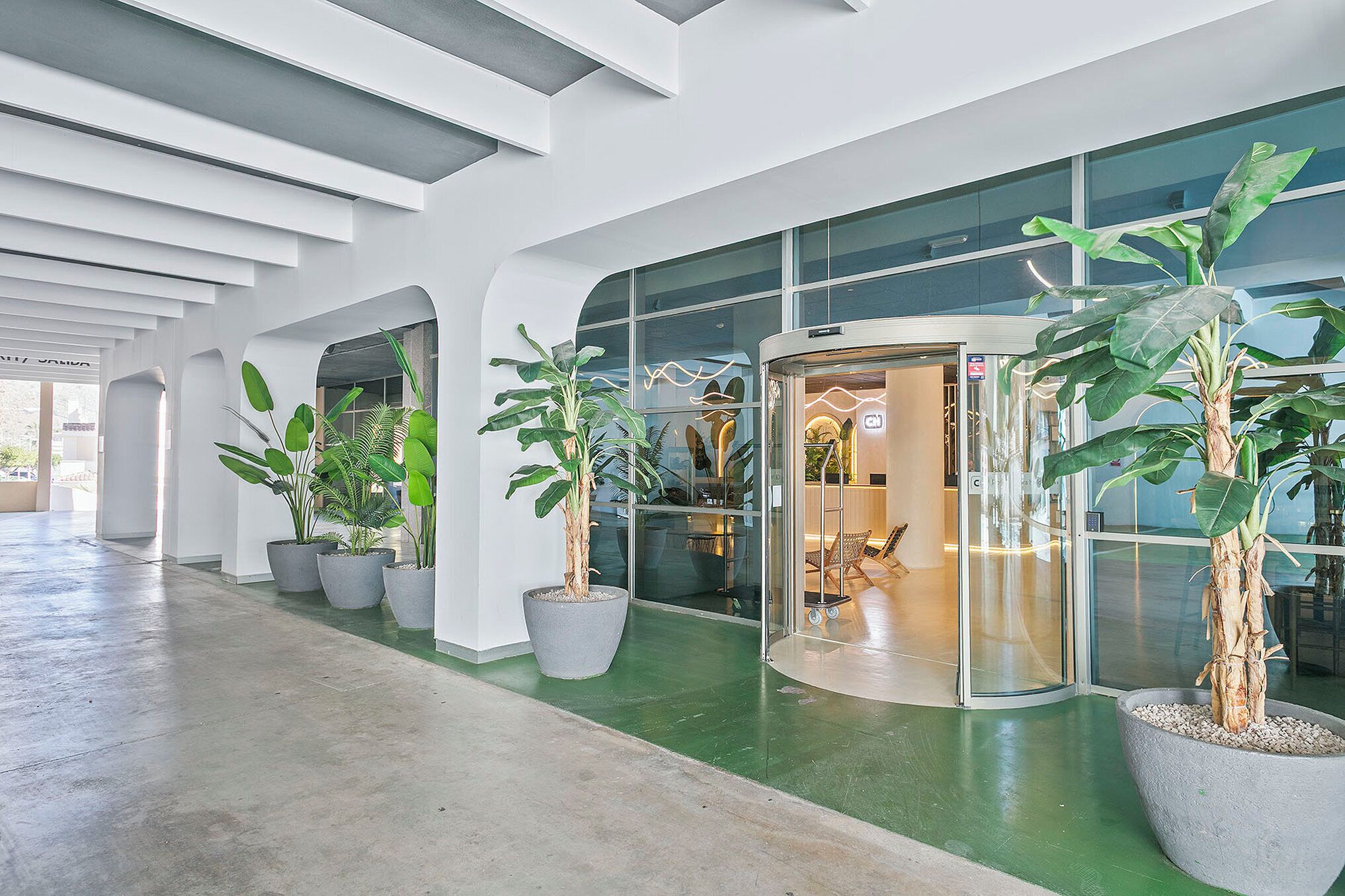 A modern interior with potted plants, a glass elevator, and a curved wall.