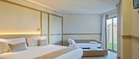 A hotel room with a large bed, a smaller bed, a sofa, and a large window.