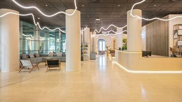 Un lobby espacioso con mostrador de recepción, zona de estar y vistas al exterior.