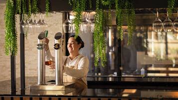 A bar area with a bartender serving drinks, a beer tap, and hanging glassware.