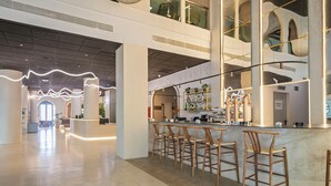 A modern bar area with a marble countertop, wooden bar stools, and a visible bar stocked with bottles. - Cullera Holiday Hotel (Cullera)