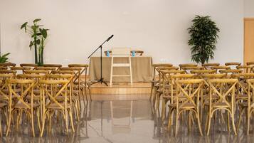 A room with a stage, chairs, and plants.