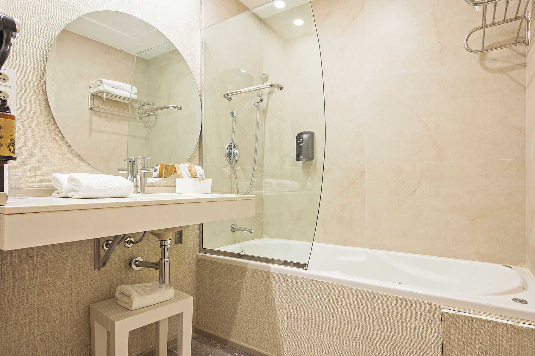 A modern bathroom with a glass-enclosed shower, a large mirror, a white sink, and a bathtub.