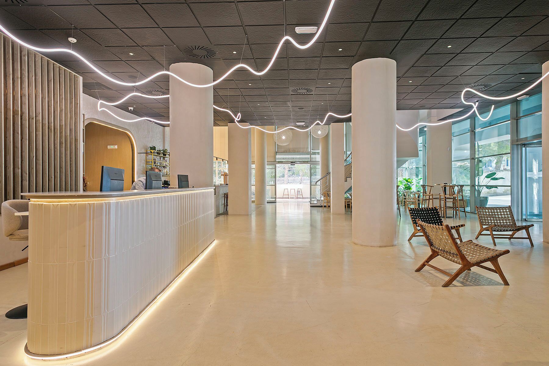 A spacious lobby with a reception desk, large columns, and a view of the outdoors through large windows.