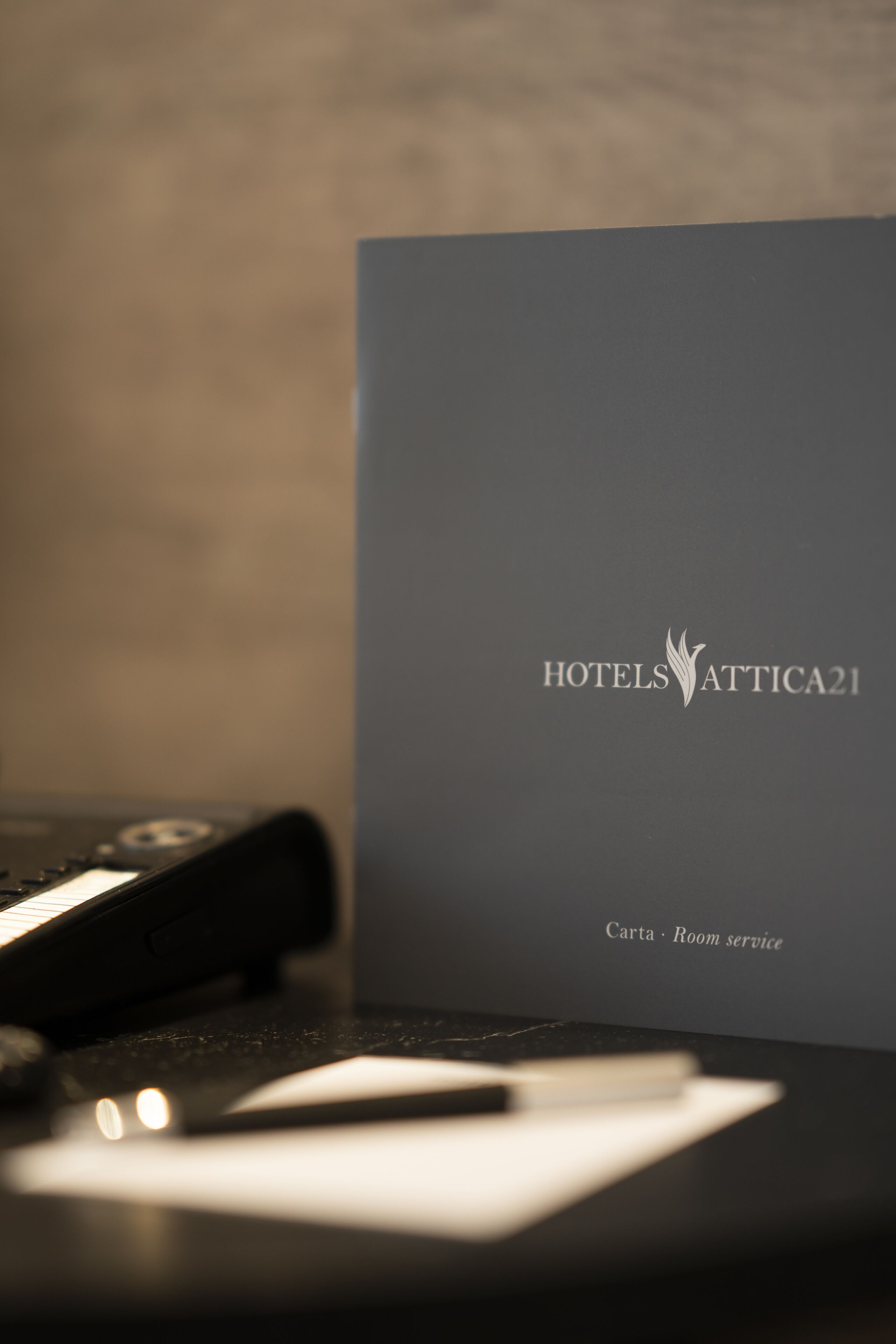 Habitación de hotel con un escritorio negro, un teléfono negro y una libreta blanca.