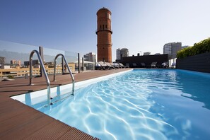 Ein Pool auf dem Dach mit freiem Blick auf einen hohen Ziegelturm im Hintergrund.