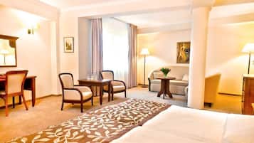 Ein Hotelzimmer mit einem Bett, einem Schreibtisch mit Stühlen, einer Couch und einem kleinen Tisch mit Lampe.