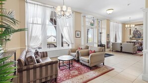 A spacious hotel lobby with a striped sofa, armchairs, a round table, and a chandelier. - The Ugadale Hotel and Cottages (Campbeltown)