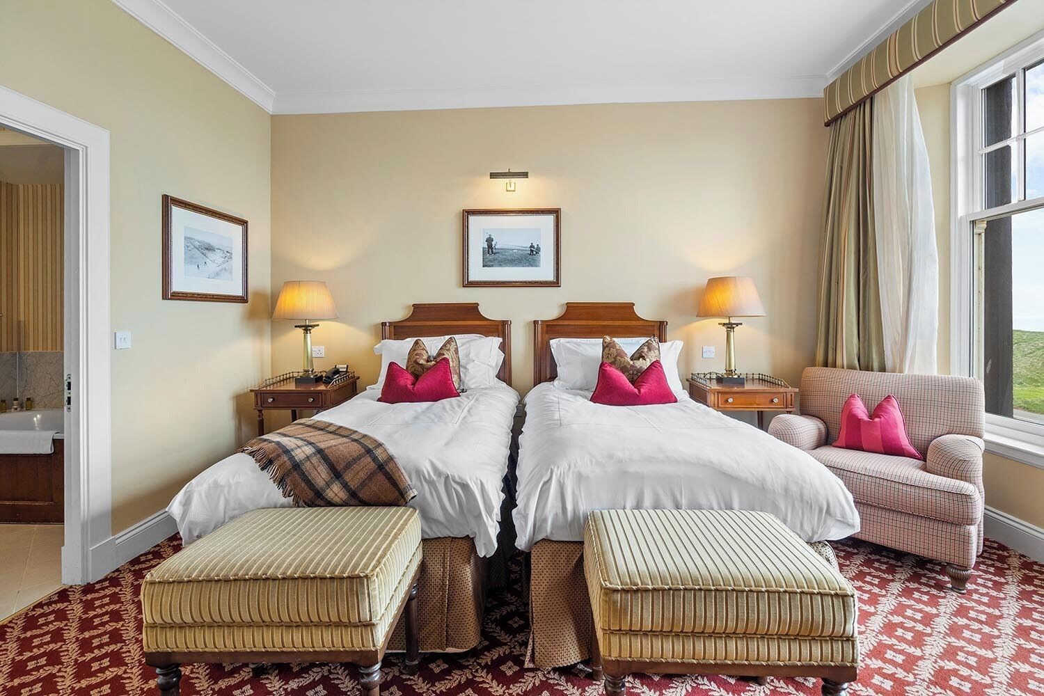 A double bed with two nightstands, a chair, and a window with curtains.