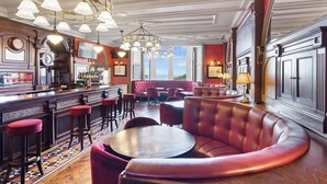 A luxurious bar area with a curved seating arrangement, a bar counter, and a large window providing a view. - The Ugadale Hotel and Cottages (Campbeltown)