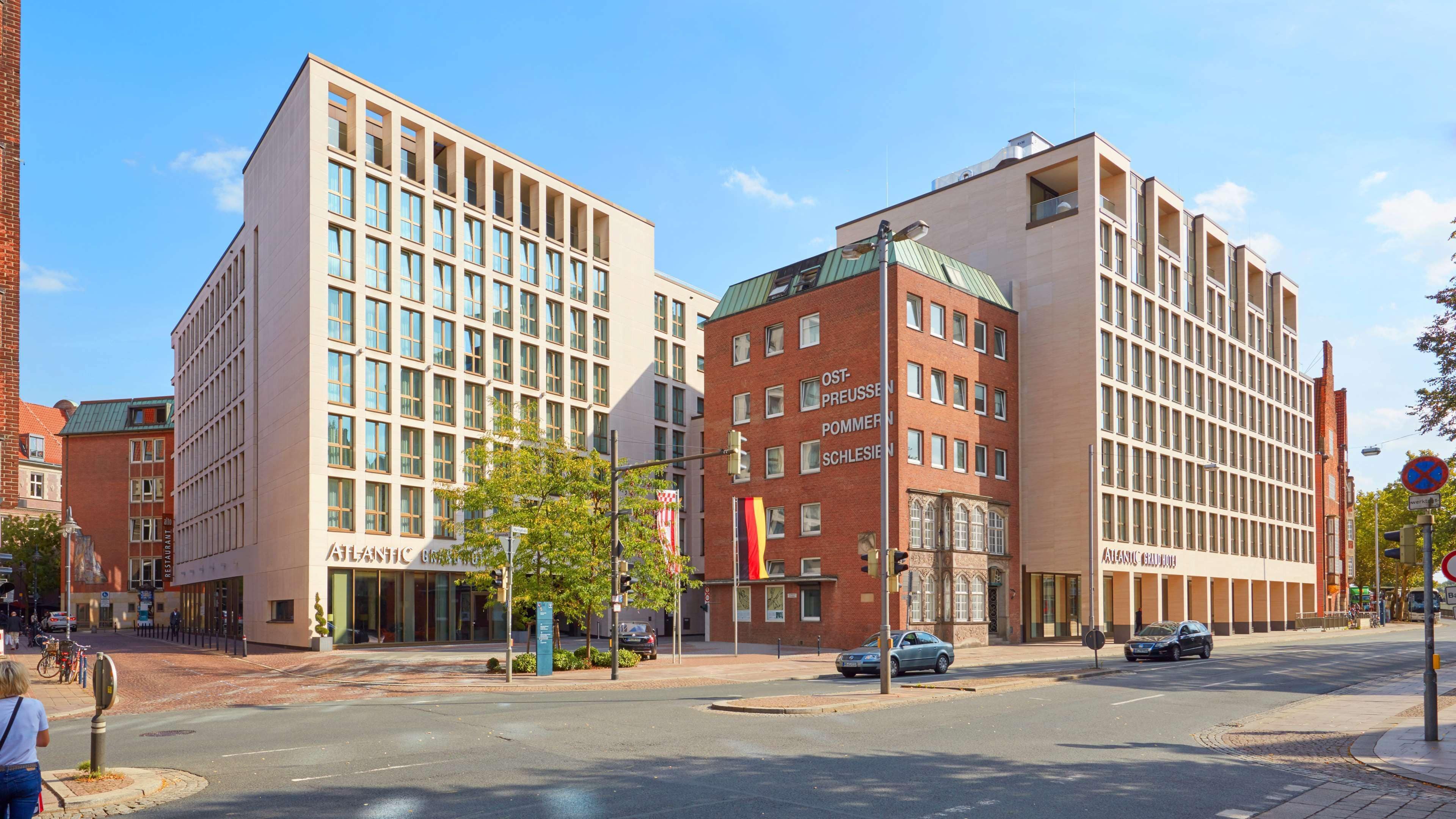 A modern hotel with a glass facade, a brick building with a green roof, and a sign for 'Atlantic Restaurant'.