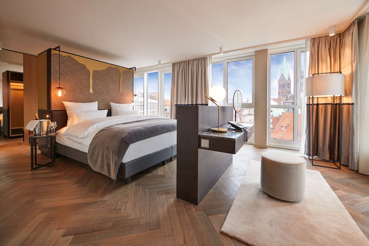 Une chambre d’hôtel moderne dotée d’un grand lit, d’un bureau, d’une chaise et offrant une vue sur le paysage urbain.