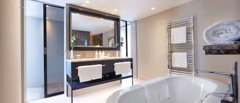 A modern bathroom with a large bathtub, a double vanity with two sinks, and a large mirror.