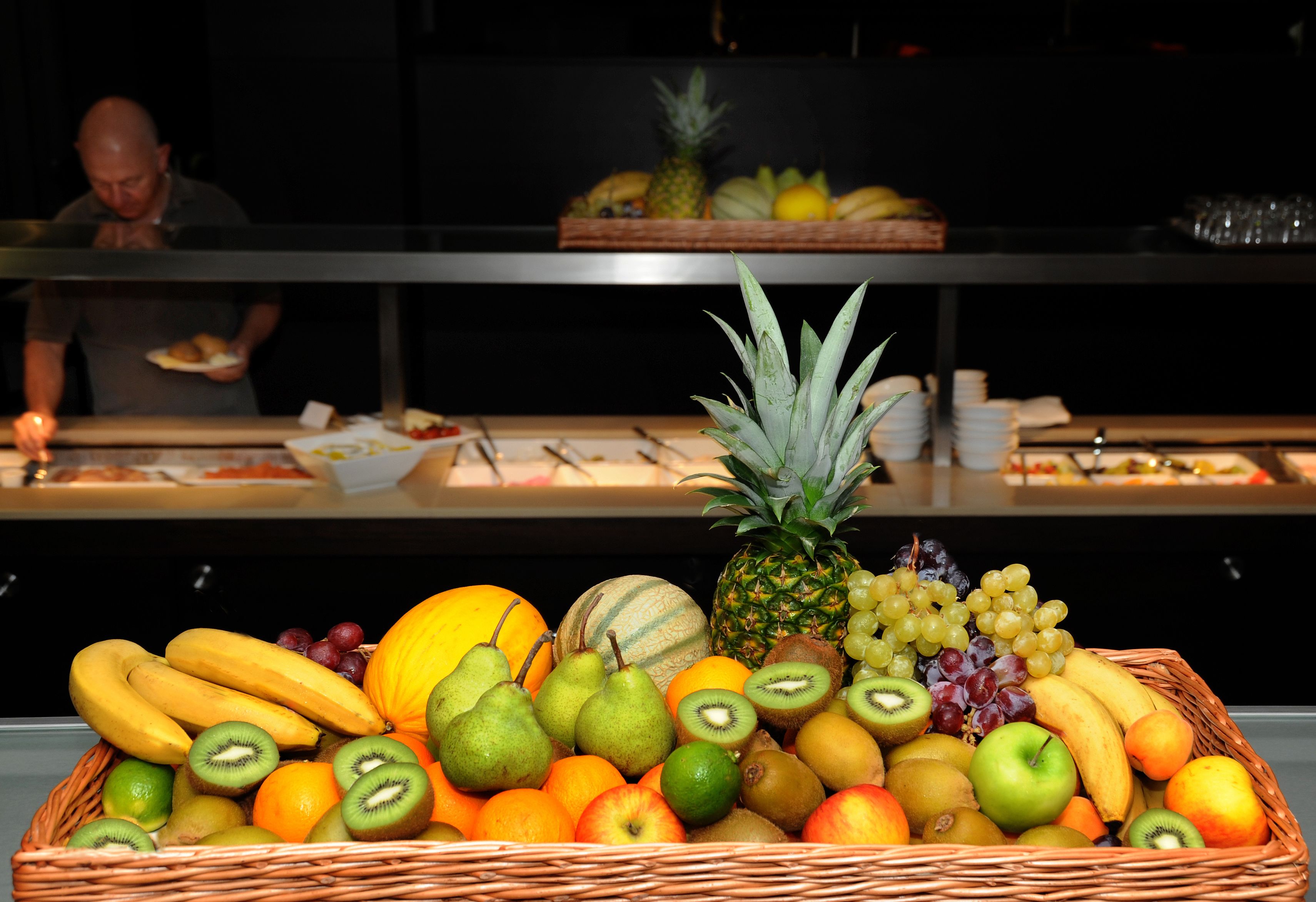 Eine Obstschale mit verschiedenen Früchten, darunter Bananen, Trauben und Äpfel.