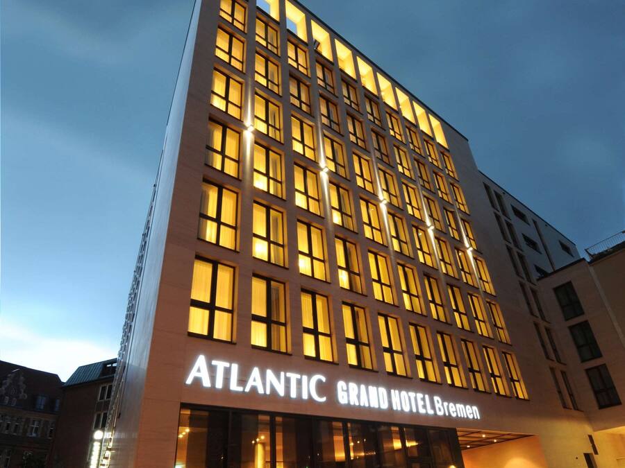 La fachada moderna del Hotel Atlantic Grand Bremen, con amplios ventanales y una entrada destacada.