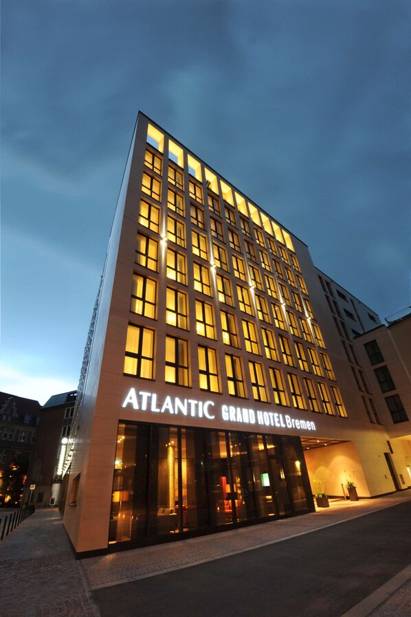 La fachada moderna del Hotel Atlantic Grand Bremen, con amplios ventanales y una entrada destacada.