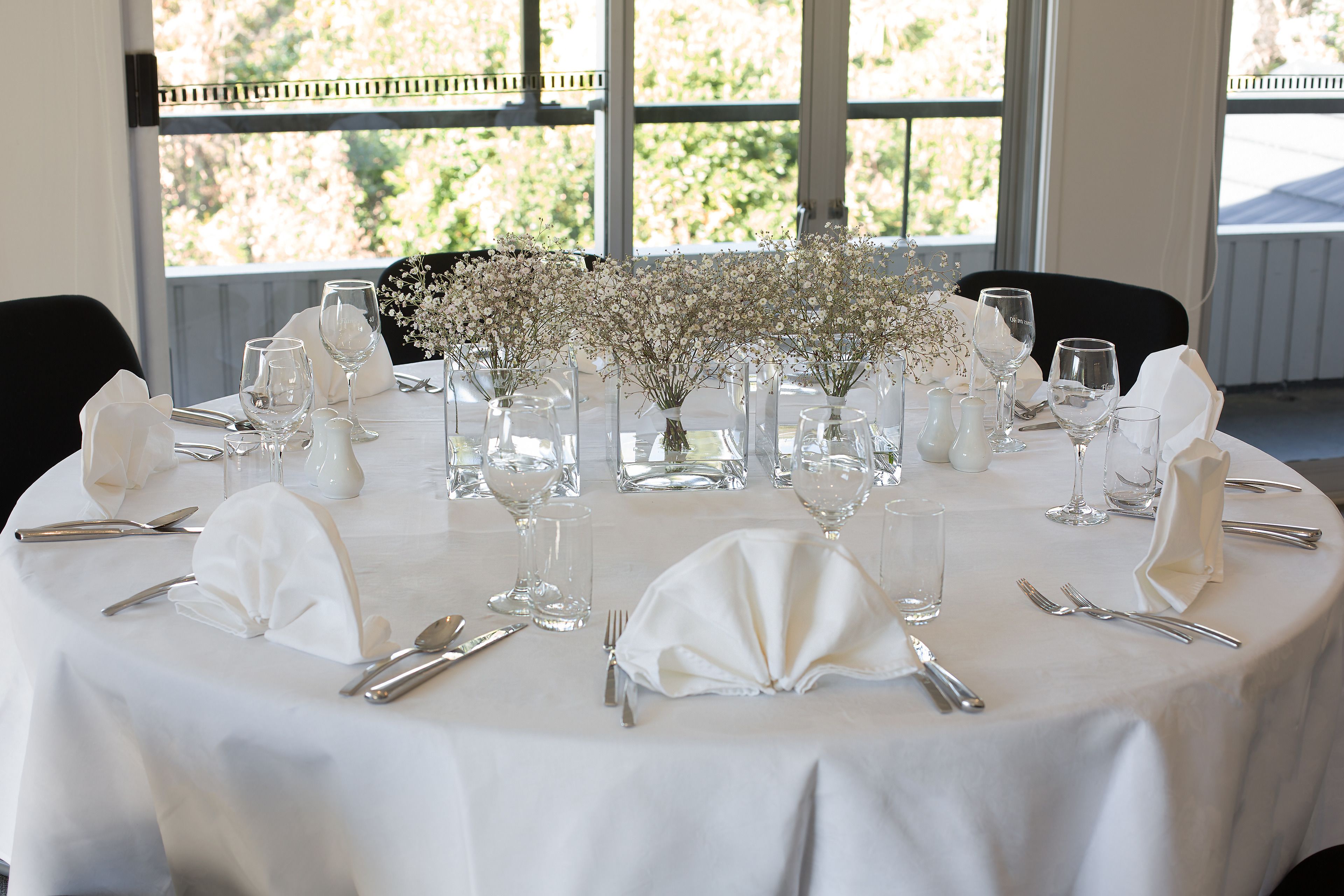 A round table set for a formal event with white tablecloth, glassware, and silverware.