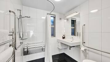 A modern bathroom with a walk-in shower, a toilet, a sink with a mirror, and a towel rack.