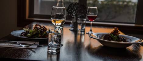 A dining table with plates of food, glasses of water and wine, and a bottle of water.