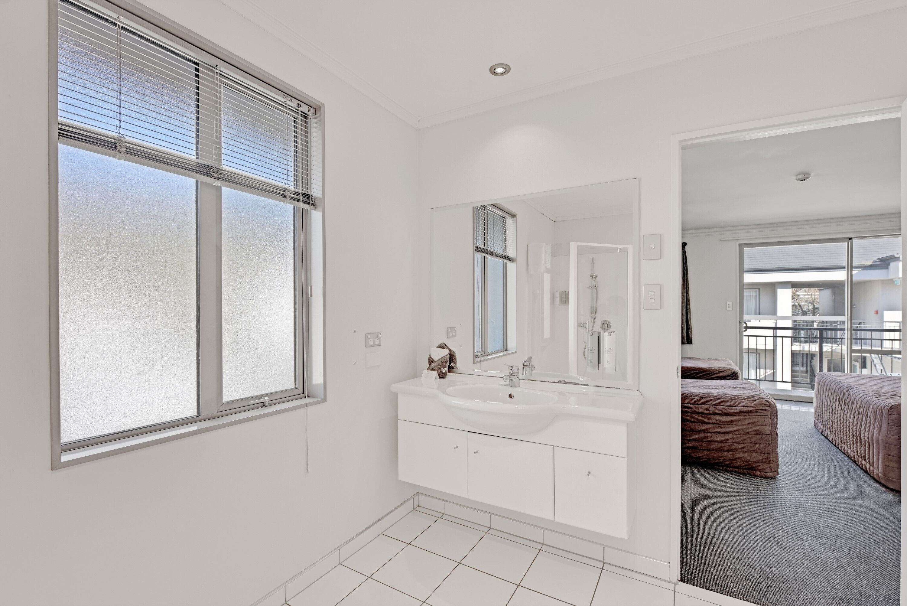 A modern bathroom with a large window, a double sink vanity, and a mirror.