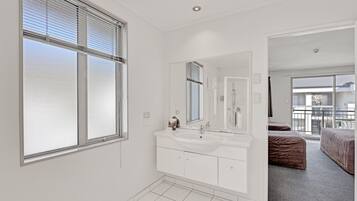 A modern bathroom with a large window, a double sink vanity, and a mirror.