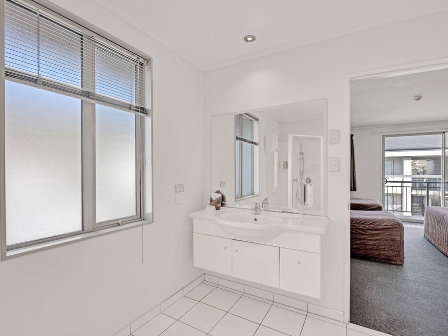 A modern bathroom with a large window, a double sink vanity, and a mirror.