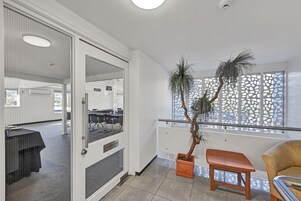 Une salle de conférence avec un sol carrelé, une plante en pot et un banc en bois.