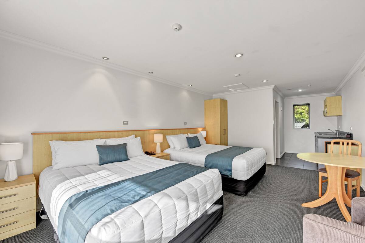 A hotel room with two beds, a desk, and a chair.