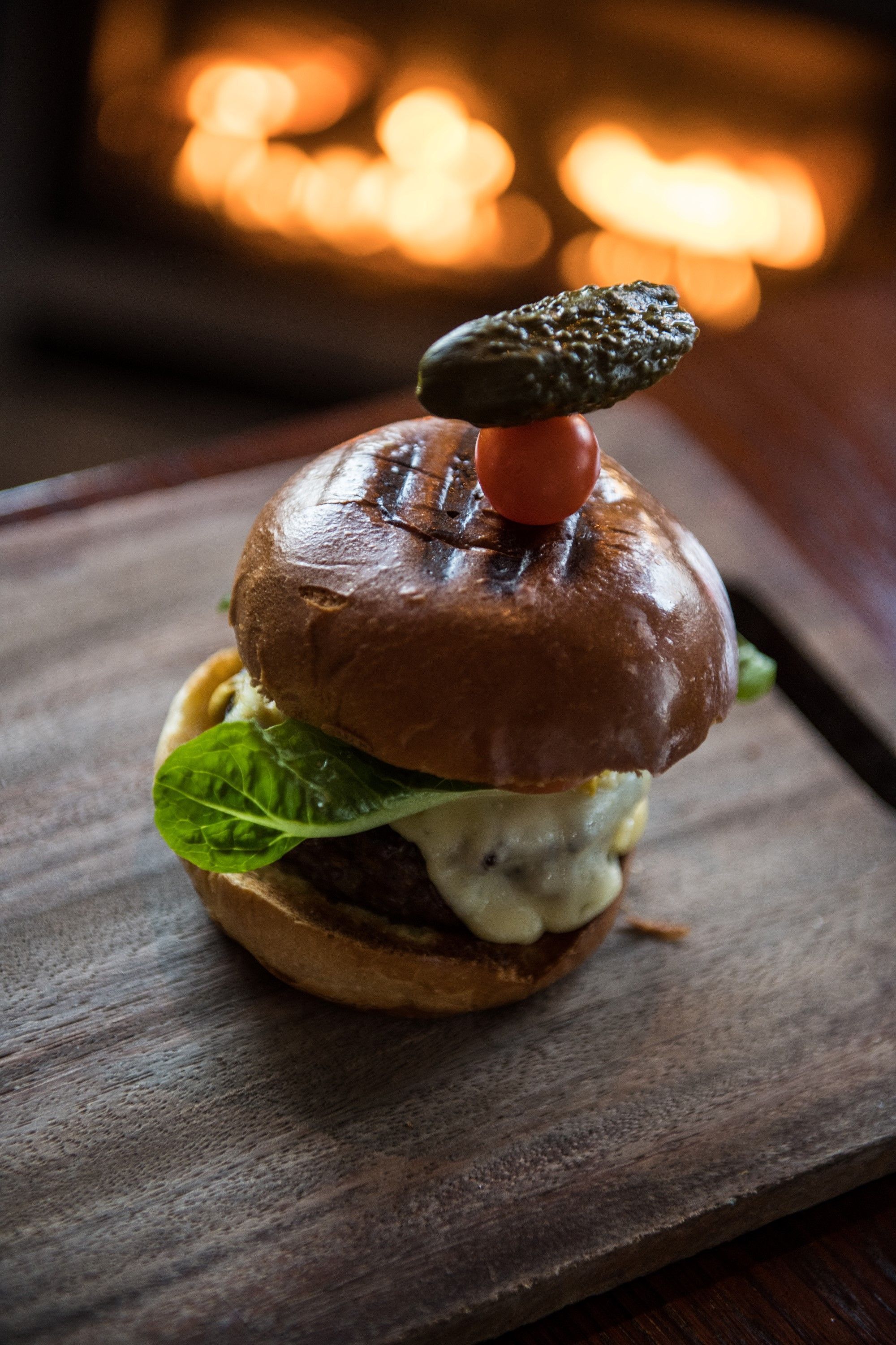 A burger with a toasted bun, lettuce, and a patty, served on a wooden board.