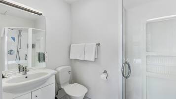 Et moderne badeværelse med hvid vask, toilet og brusebad.