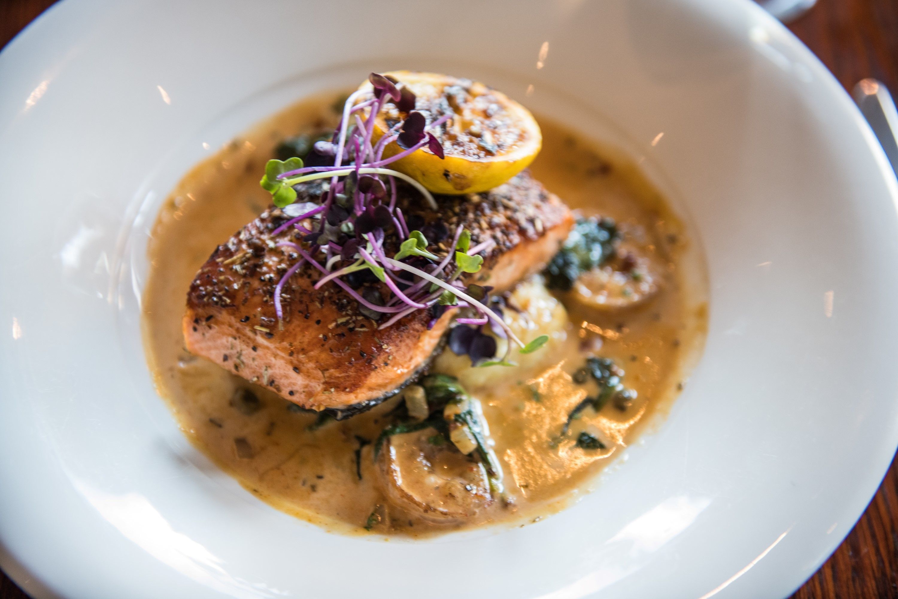 A plate of food with salmon, mushrooms, and a lemon slice.