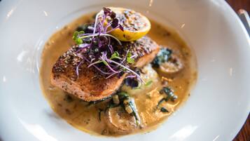 A plate of food with salmon, mushrooms, and a lemon slice.