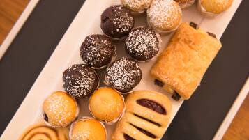 A tray of assorted pastries including chocolate balls, lemon tarts, and cinnamon rolls.