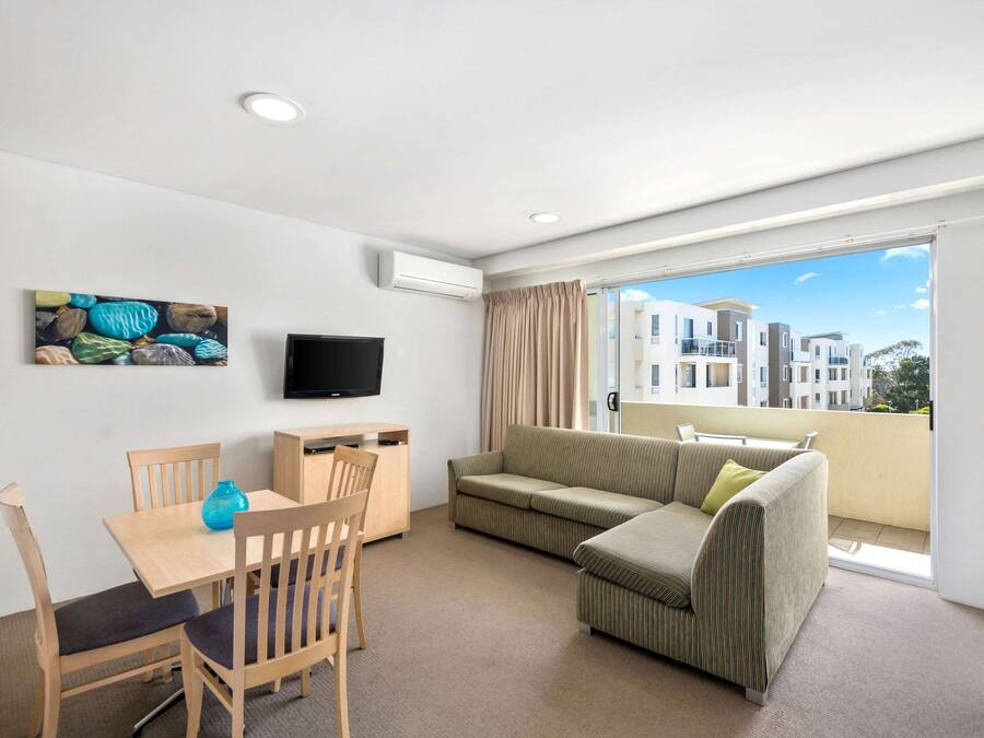 Ein modernes Wohnzimmer mit Essbereich, einem Flachbildfernseher, einer Couch und einem Balkon mit Blick auf die Stadt.