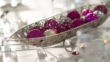 A table with a decorative bowl containing glittery ornaments, clear glassware, and candles.