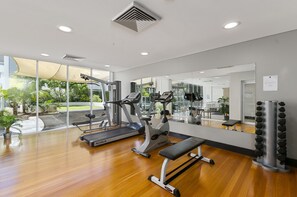 Ein modernes Fitnessstudio mit Trainingsgeräten, großen Fenstern und Holzboden.