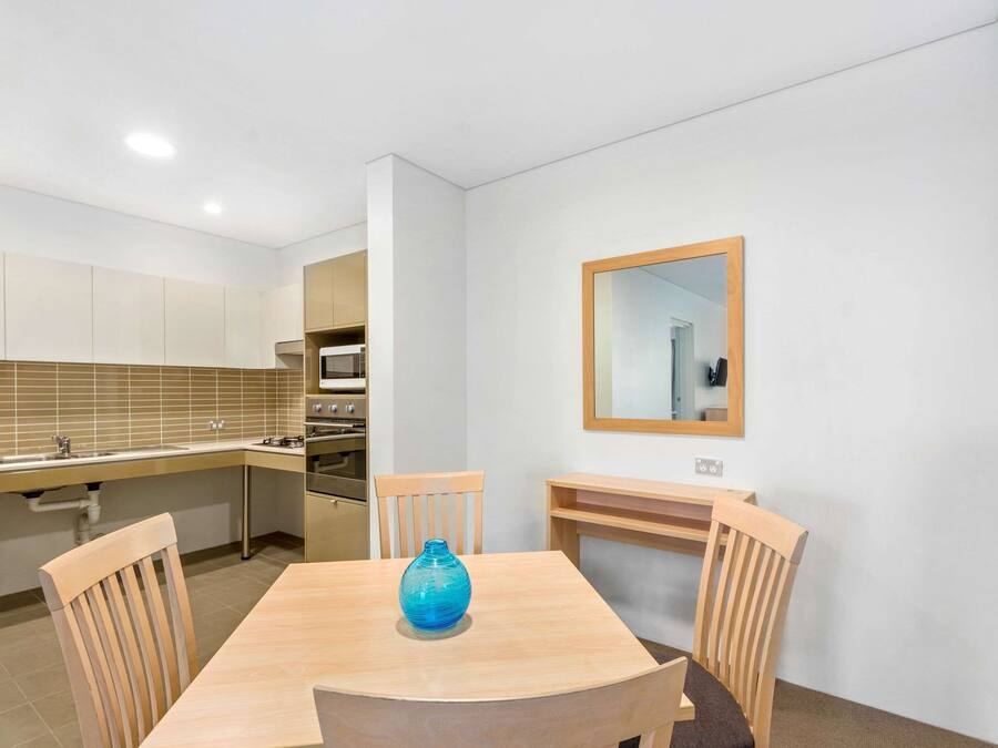 Uma cozinha compacta com área de refeições, incluindo uma mesa de madeira, cadeiras e um vaso azul.