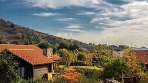 Entorno rural con casas tradicionales, una chimenea de piedra y una colina al fondo.