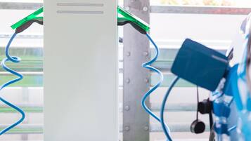Een laadstation met een groene en blauwe kabel die is aangesloten op een voertuig.