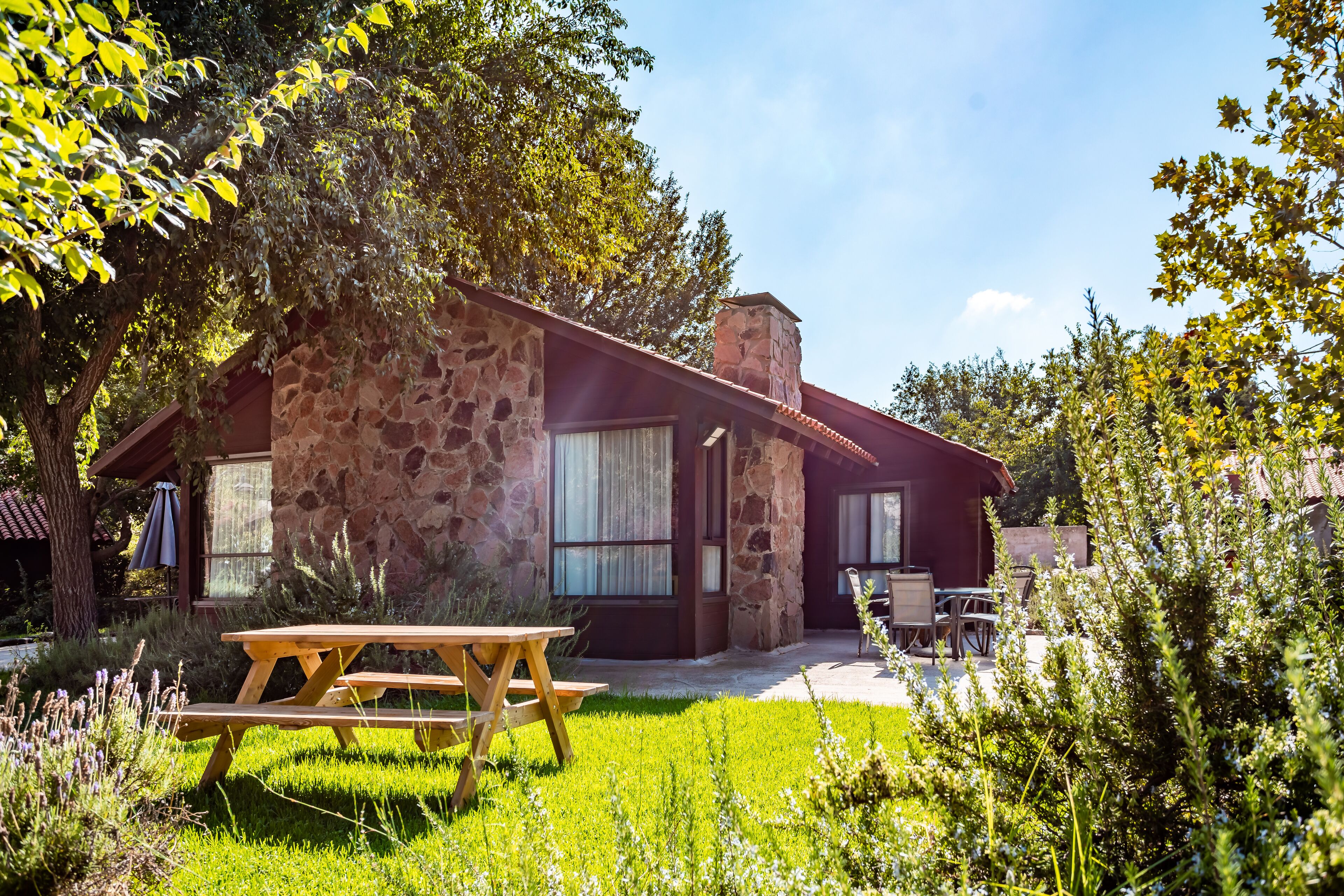 A stone house with a patio, a wooden table, and a chair.