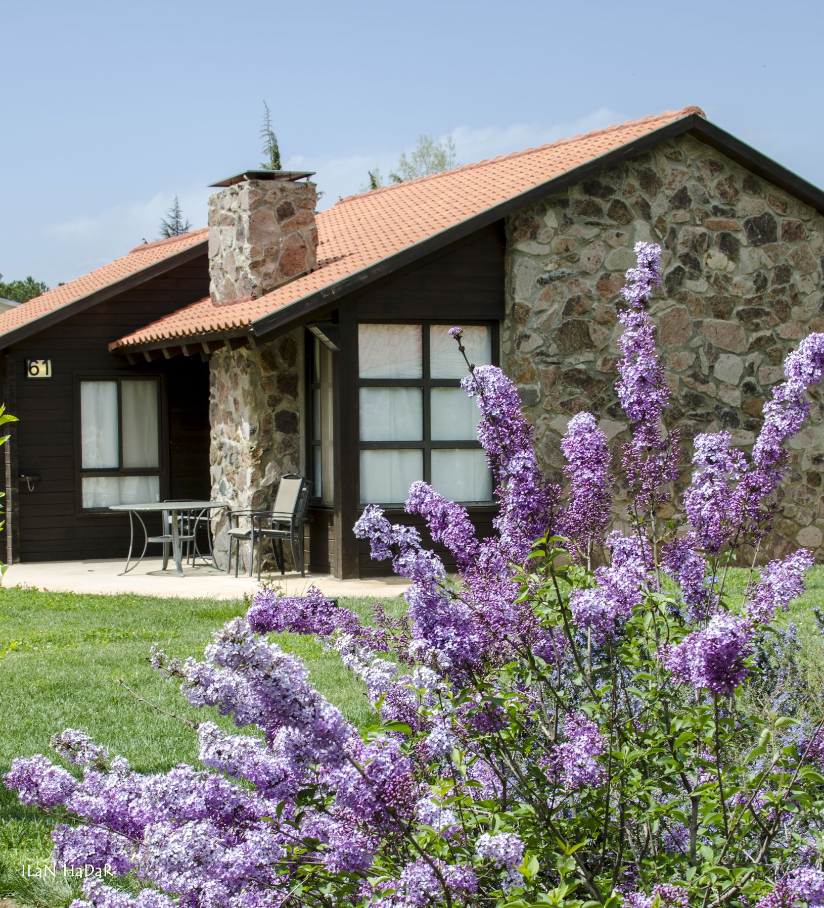 A stone building with a tiled roof, a chimney, and a patio with outdoor furniture.