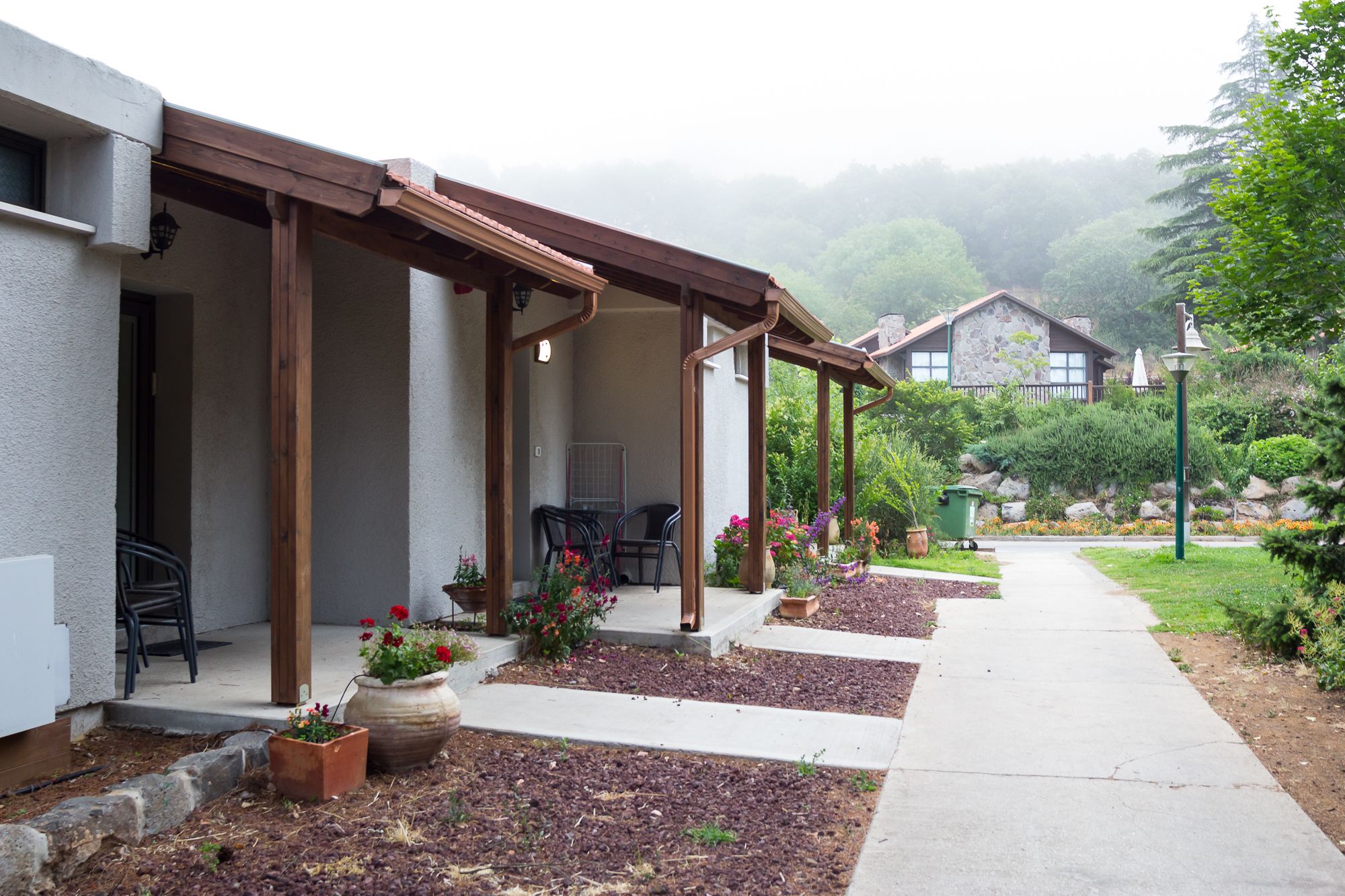 Un espacio al aire libre cubierto con sillas y plantas en macetas, que conduce a un edificio de fachada de piedra.