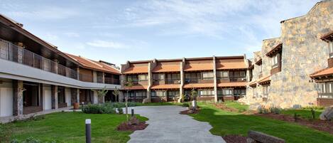 A courtyard with a central pathway, surrounded by multi-story buildings with balconies and stone facades.