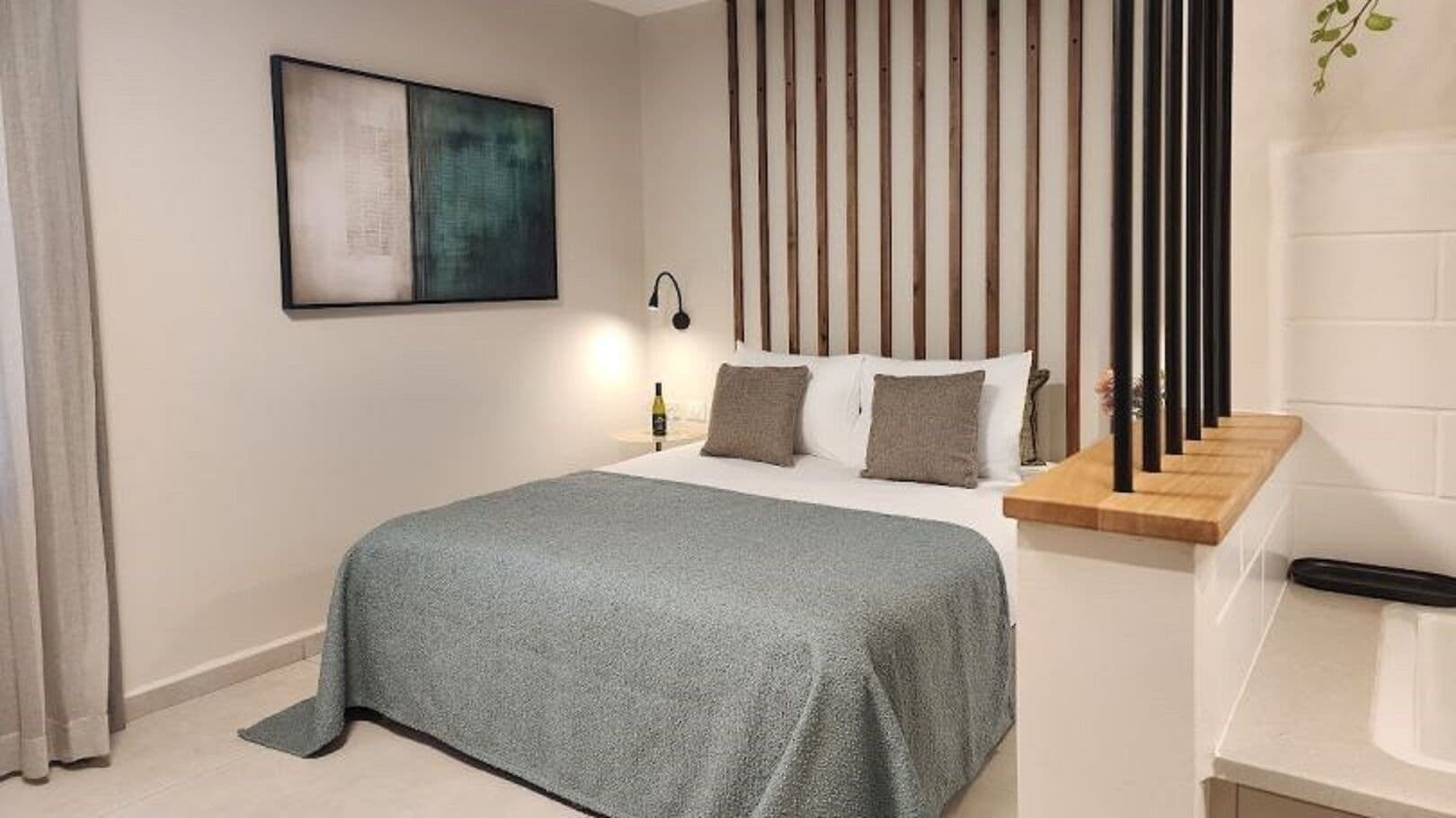 Un dormitorio moderno con una cama, una mesita de noche, una lámpara y un cuadro en la pared.