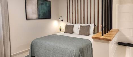 Un dormitorio moderno con una cama, una mesita de noche, una lámpara y un cuadro en la pared.