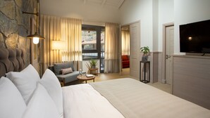Un dormitorio amplio con una cama grande, un televisor y vistas al exterior a través de una ventana.