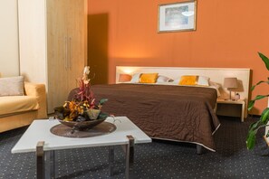 A hotel room with a bed, a bedside table with a lamp, a small table with a decorative bowl, a sofa, and a large potted plant. - Hotel Pacific Timisoara (Timisoara)
