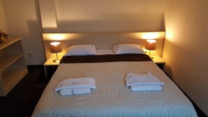 A hotel room with a neatly made bed, two bedside lamps, and a shelf with a plant. - Hotel Pacific Timisoara (Timisoara)