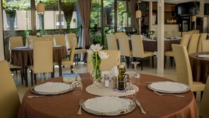 A dining area with round tables set for four, each with a white lace doily, silverware, and wine glasses. - Hotel Pacific Timisoara (Timisoara)