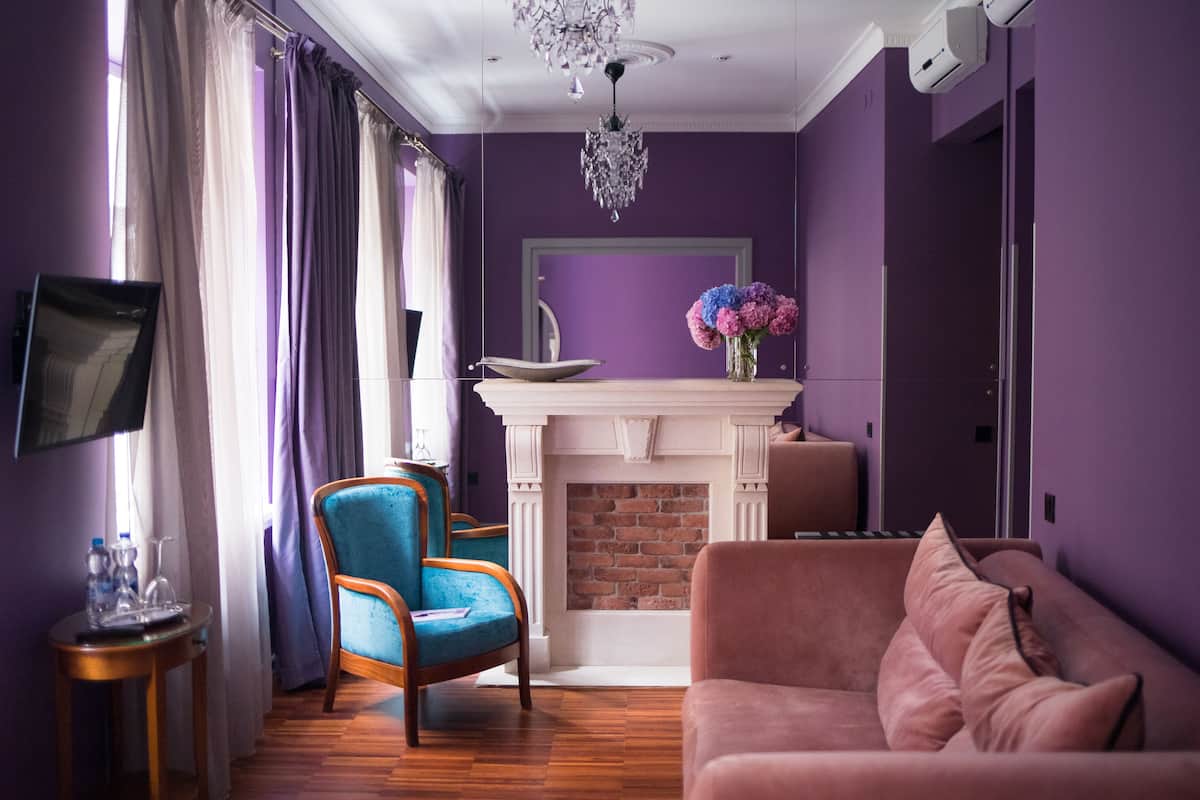 Une pièce avec une cheminée, un canapé, un fauteuil et un téléviseur fixé au mur.